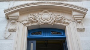 Entrada de un edificio con puerta azul, detalles ornamentales blancos y un arco decorativo.