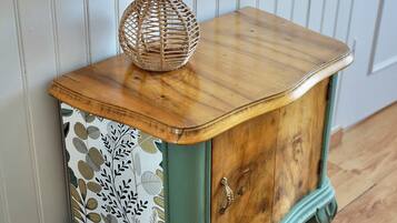 Une table d’appoint en bois, de style vintage, agrémentée d’un abat-jour tissé, d’un panneau décoratif et d’un tiroir.