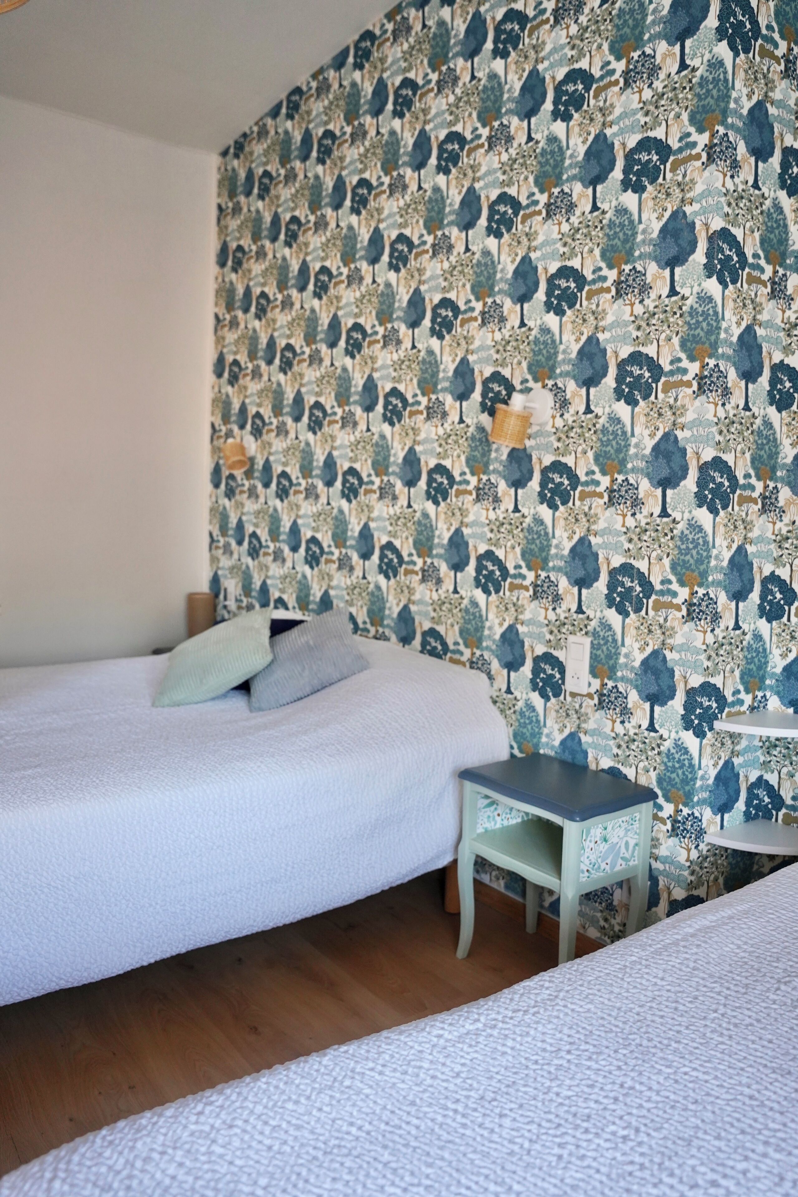 Une chambre à coucher avec un papier peint à motifs, un lit, une petite table et une chaise.