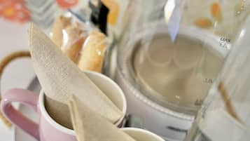 Un plateau avec deux tasses, une rose et une blanche, contenant des sachets de thé et une théière.