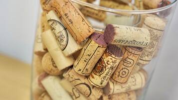 A clear glass container filled with various corks, some with labels and some without.