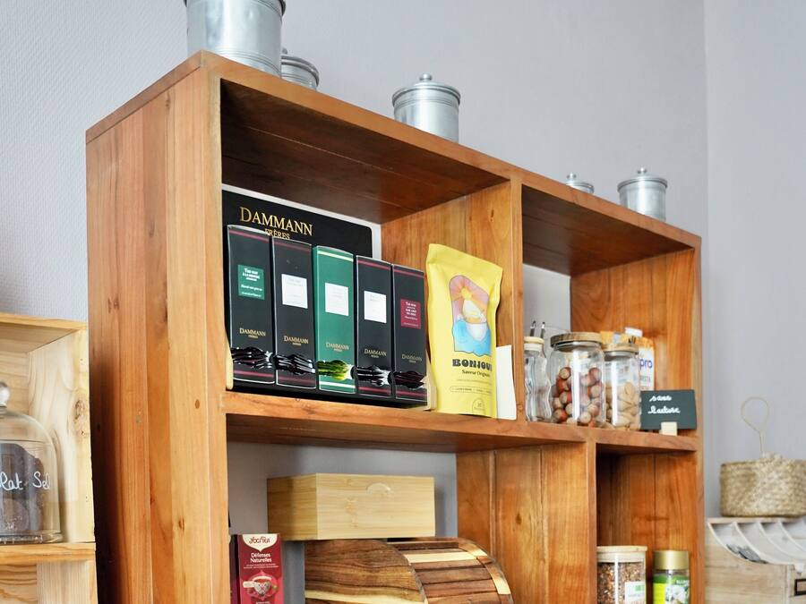 A wooden shelf unit with various food items, glassware, and storage containers.
