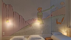 Una habitación con dos camas, un mural de una persona en la montaña y un conejo.