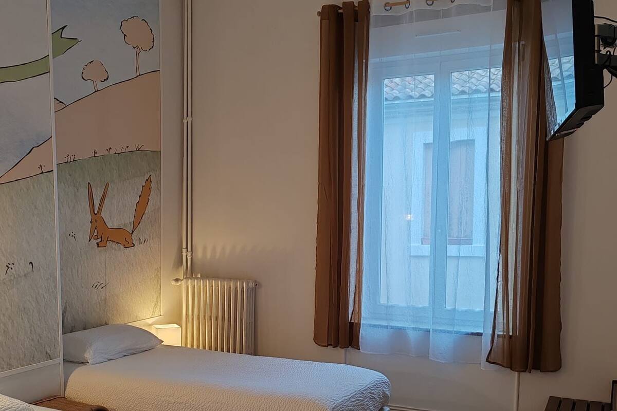 A hotel room with two beds, a large window with curtains, a flat-screen TV mounted on the wall, and a radiator.