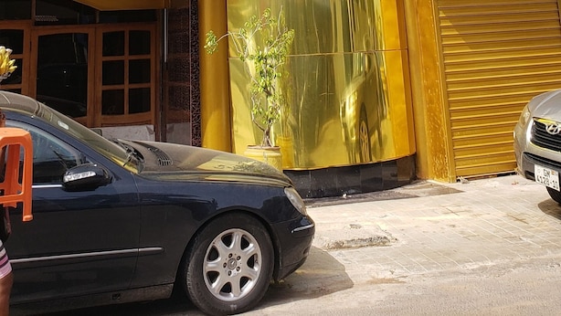 Un bâtiment doté d’une structure cylindrique en verre remarquable, avec une façade jaune et beige, et une voiture garée devant.