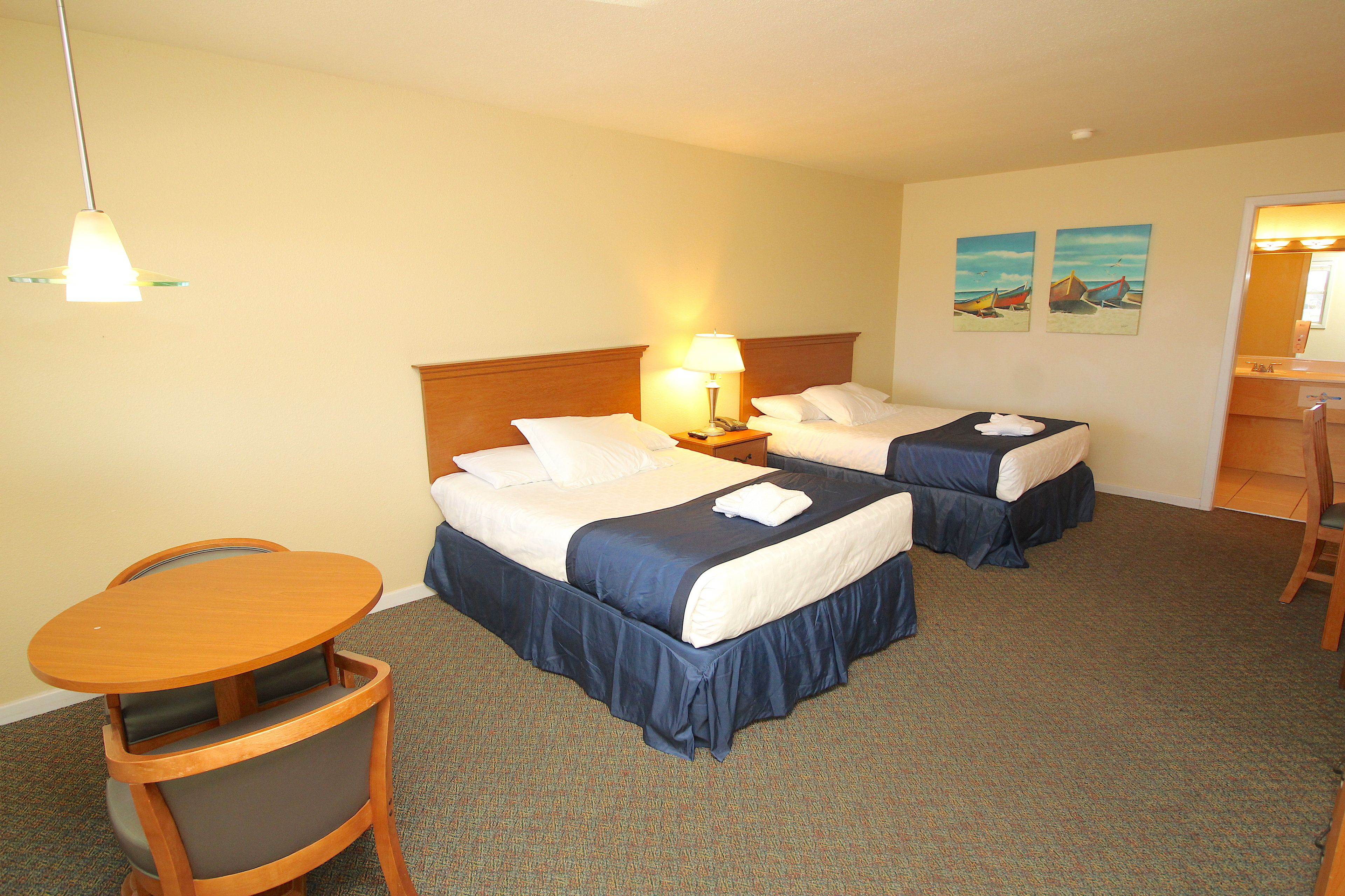 A hotel room with two beds, a desk, and a chair.
