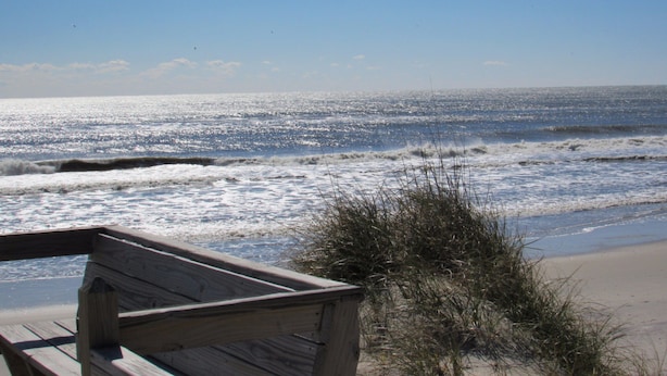 A wooden bench overlooking a beach with waves and a clear sky. - Sea Gull By Kees Vacations (Hatteras)