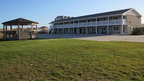 A motel with a two-story building, a covered outdoor seating area, and a grassy lawn. - Sea Gull By Kees Vacations (Hatteras)