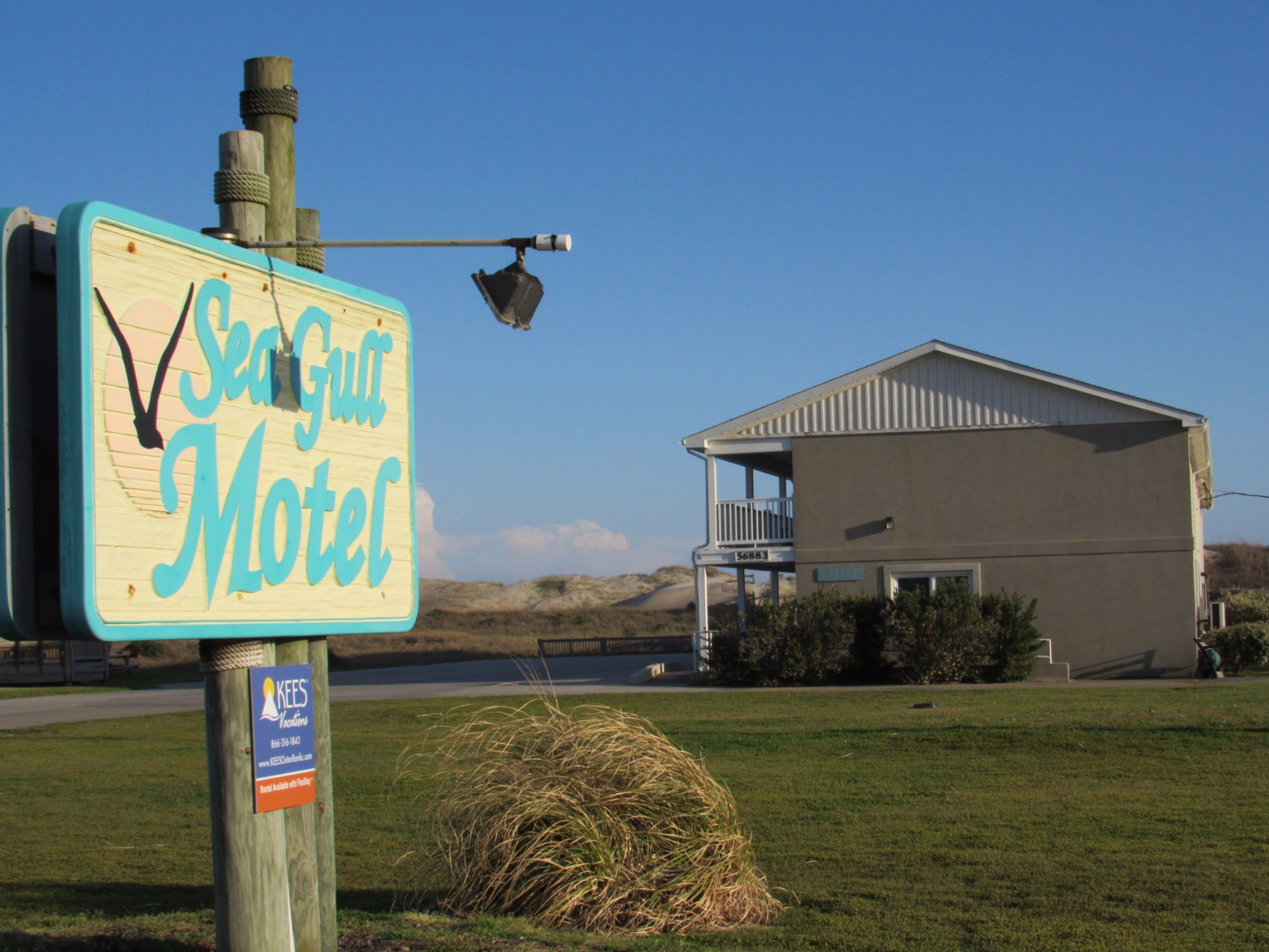 Letrero de motel con vista a la playa, un fardo de heno y un edificio con balcón.