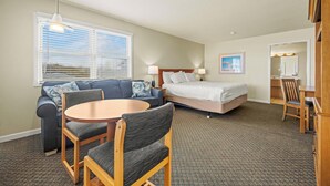 A hotel room with a bed, a sofa, a dining table, and a chair. - Sea Gull By Kees Vacations (Hatteras)