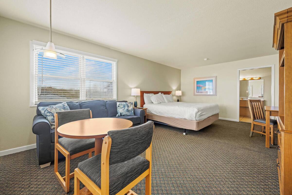 Ein Hotelzimmer mit Bett, einer Couch, einem Esstisch und einem Stuhl.