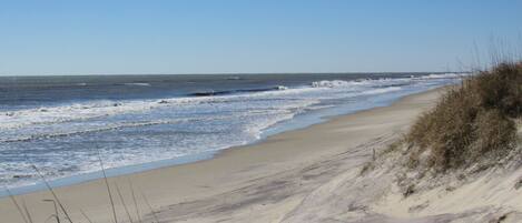 A sandy beach with gentle waves and dunes.