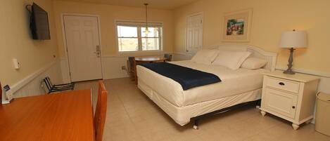 A bedroom with a bed, bedside table, lamp, and a window.