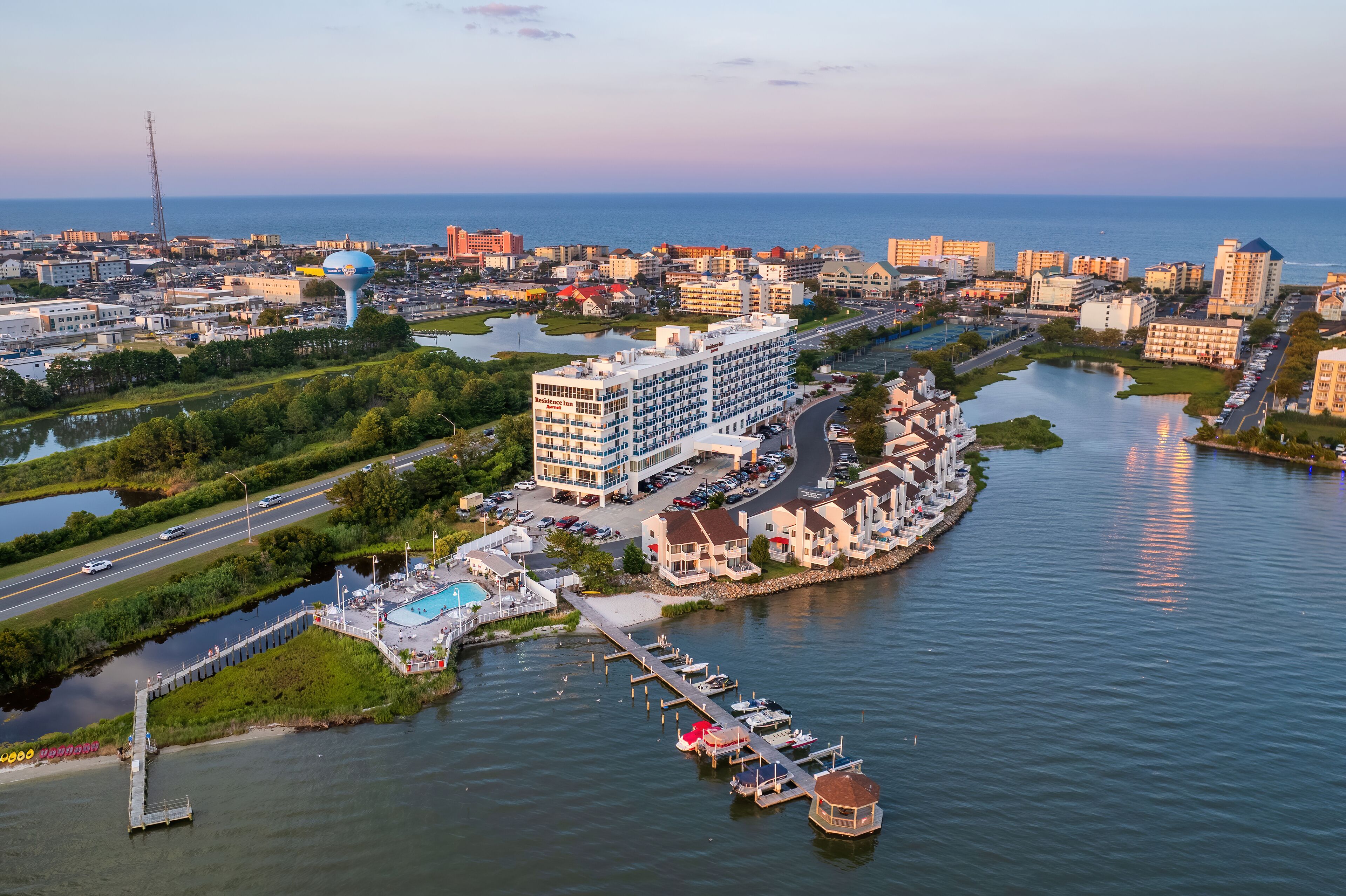 A coastal hotel with a marina, a large building with multiple floors, and a view of the sea.