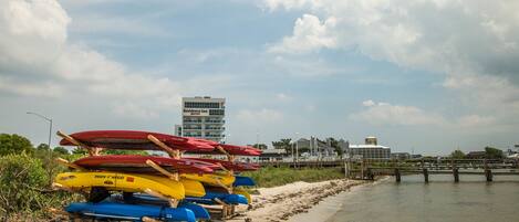 A beach with a row of colorful kayaks and a building in the background.