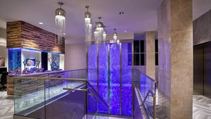 A modern hotel lobby with a glass railing, a blue-lit water feature, and a wooden wall. - Residence Inn by Marriott Ocean City (Ocean City)