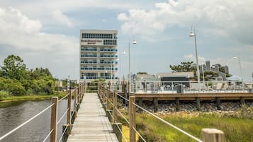 A wooden boardwalk leading to a waterfront area with a Marriott Residence Inn building in the background.