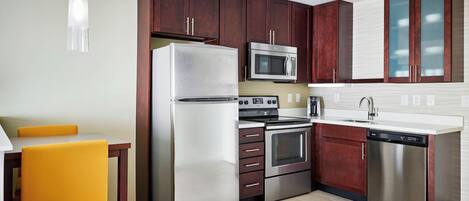 Una cocina moderna con electrodomésticos de acero inoxidable, armarios de madera y una silla amarilla.