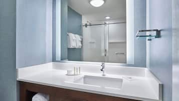 A modern bathroom with a large mirror, two sinks, and a glass shower enclosure.