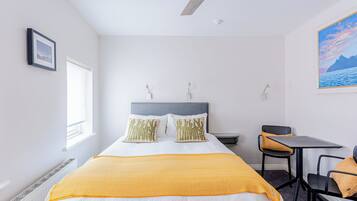 A bedroom with a bed, a desk, and a chair.