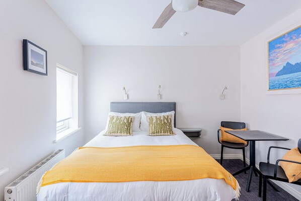 Quarto com cama, escrivaninha e cadeira.
