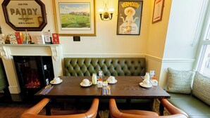 A dining area with a fireplace, a framed painting, and a poster on the wall. - Dan Linehans Bar and B&B (Killarney)