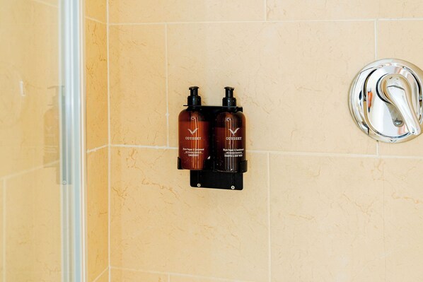 A bathroom with two black bottles labeled 'ODISSEY Black Pepper & Sandalwood' on a wall-mounted holder. - Dan Linehans Bar and B&B (Killarney)