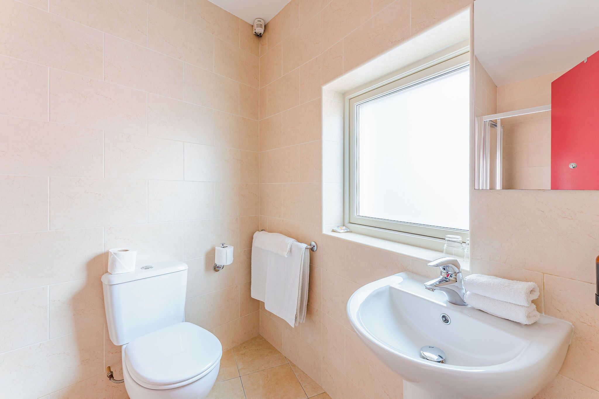 Une salle de bain avec des toilettes, un lavabo et une fenêtre.