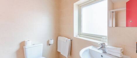 Une salle de bain avec des toilettes, un lavabo et une fenêtre.