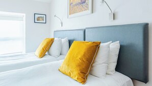 A hotel room with a large bed, two pillows, a headboard, a window, and a painting on the wall. - Dan Linehans Bar and B&B (Killarney)
