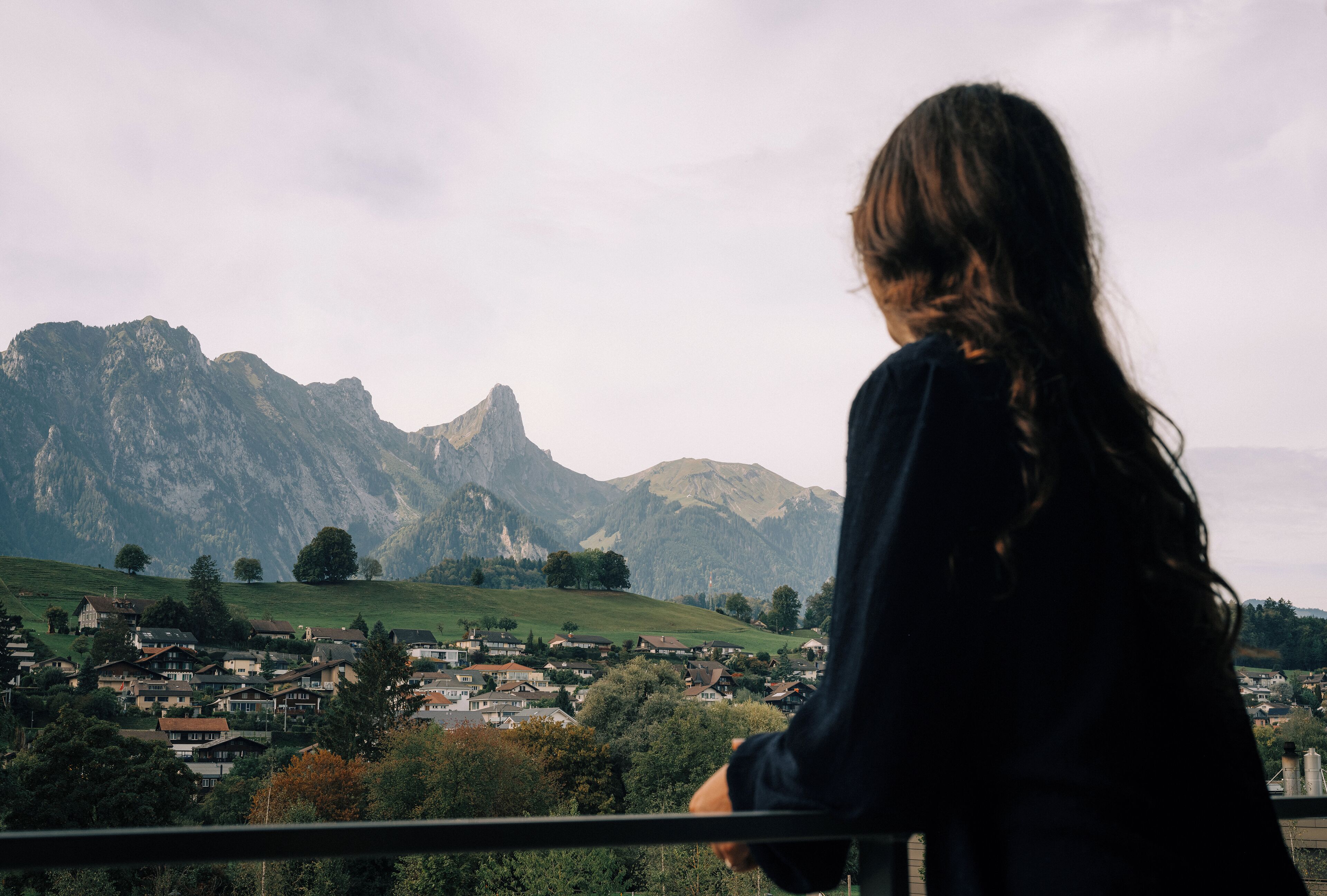 A person overlooking a town with mountains in the background.