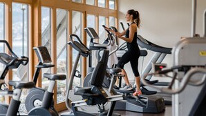 A gym with multiple treadmills and exercise equipment, large windows, and a view of the outdoors.