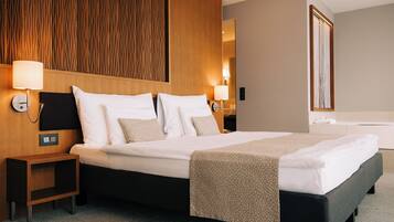 Una habitación de hotel con una cama grande, dos mesitas de noche, un cabecero de madera y un espejo.