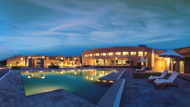 Un hotel moderno con una piscina grande y un área de descanso al aire libre.