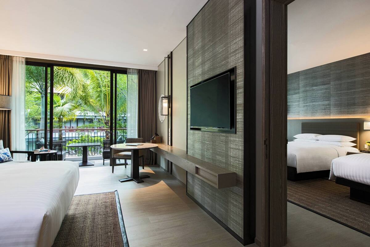A modern hotel room with a large bed, a desk, and a TV mounted on the wall.