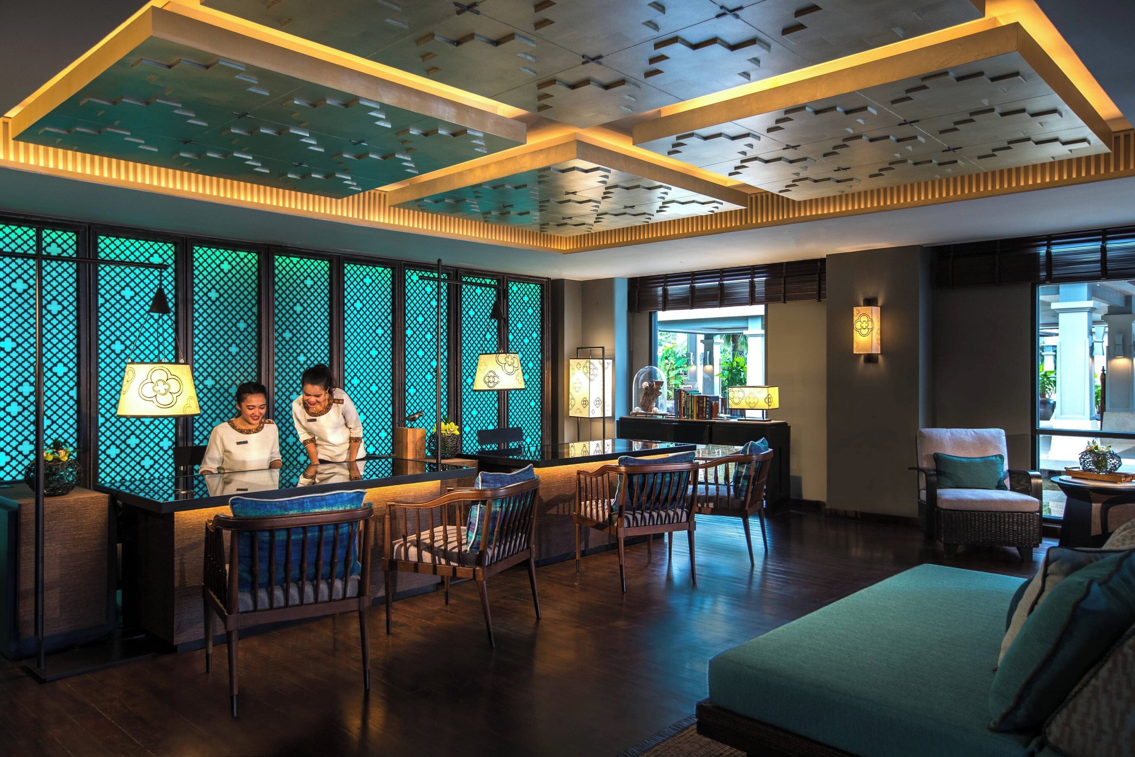 A hotel lobby with a reception desk, seating area, and large windows.