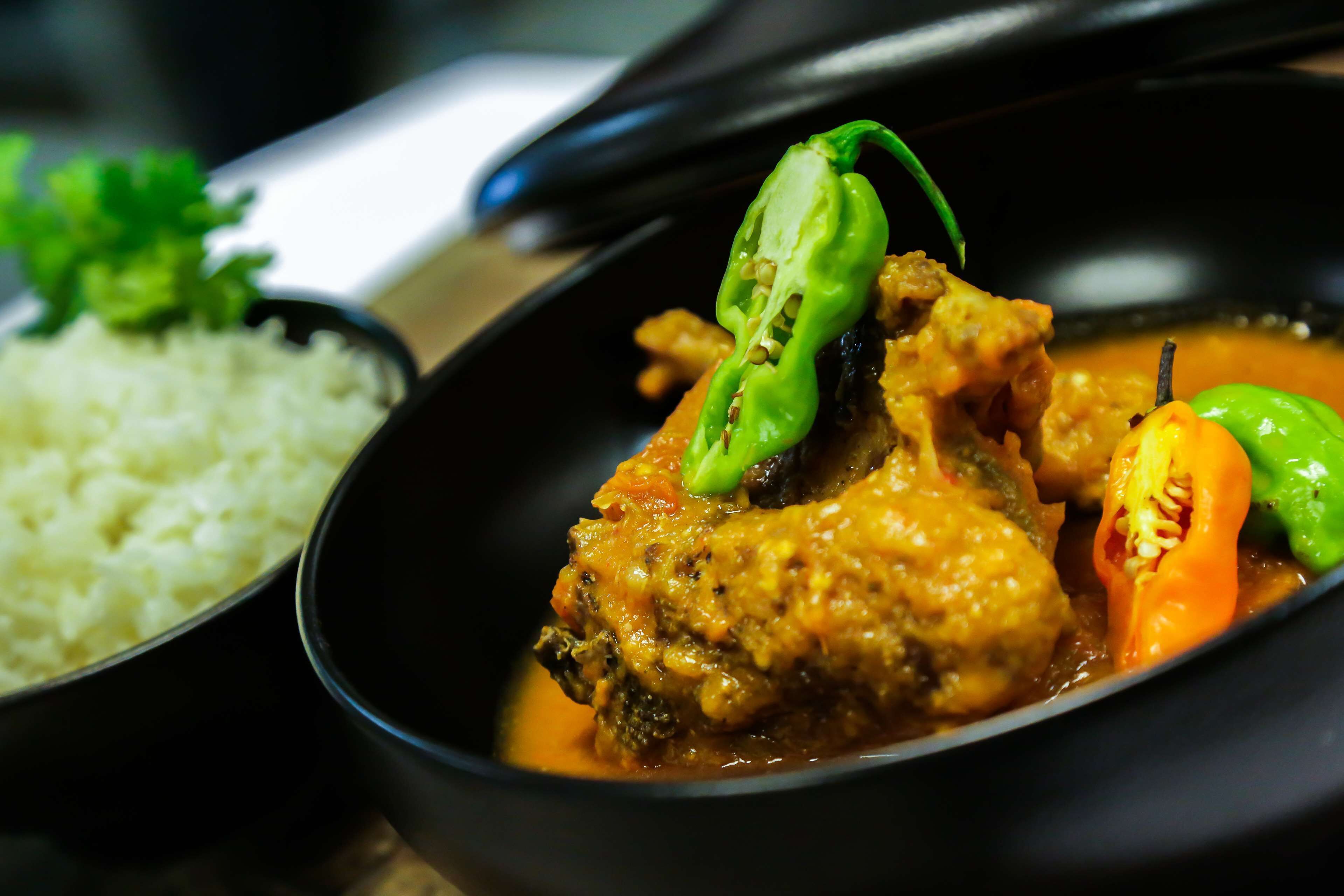 A bowl of curry with vegetables and rice.