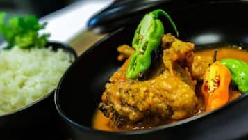 A bowl of curry with vegetables and rice.