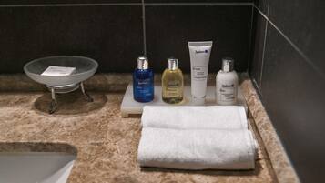 Una encimera de baño con un lavabo, tres botellas de gel de baño, champú y loción Radisson, y una toalla doblada.