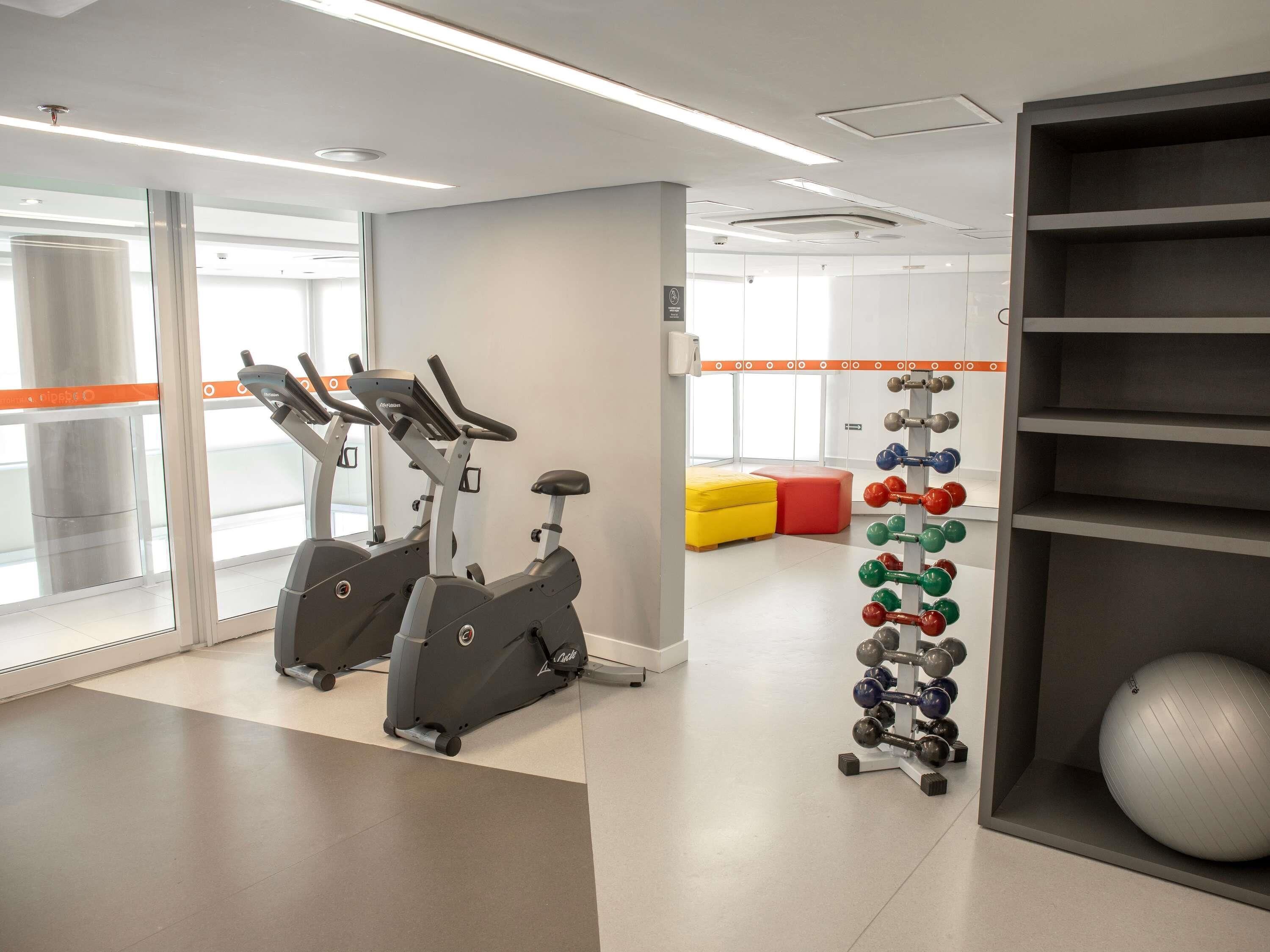 Una palestra con cyclette, un rastrello per manubri e una palla ginnastica grande.