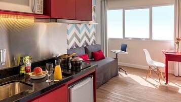 Una cocina moderna con microondas, fregadero y refrigerador. Hay un comedor con mesa y sillas, y una ventana con vistas.