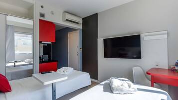 Una habitación de hotel con una cama, un escritorio, un televisor y un armario rojo.