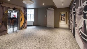 A hotel lobby with a large window, a reception desk, and a wall with a chessboard design.