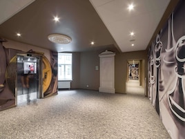 Vestíbulo de hotel con un ventanal grande, una mesa de recepción y una pared con diseño de tablero de ajedrez.