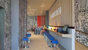 A modern bar area with a long counter, blue bar stools, and a wall with abstract black and white patterns.