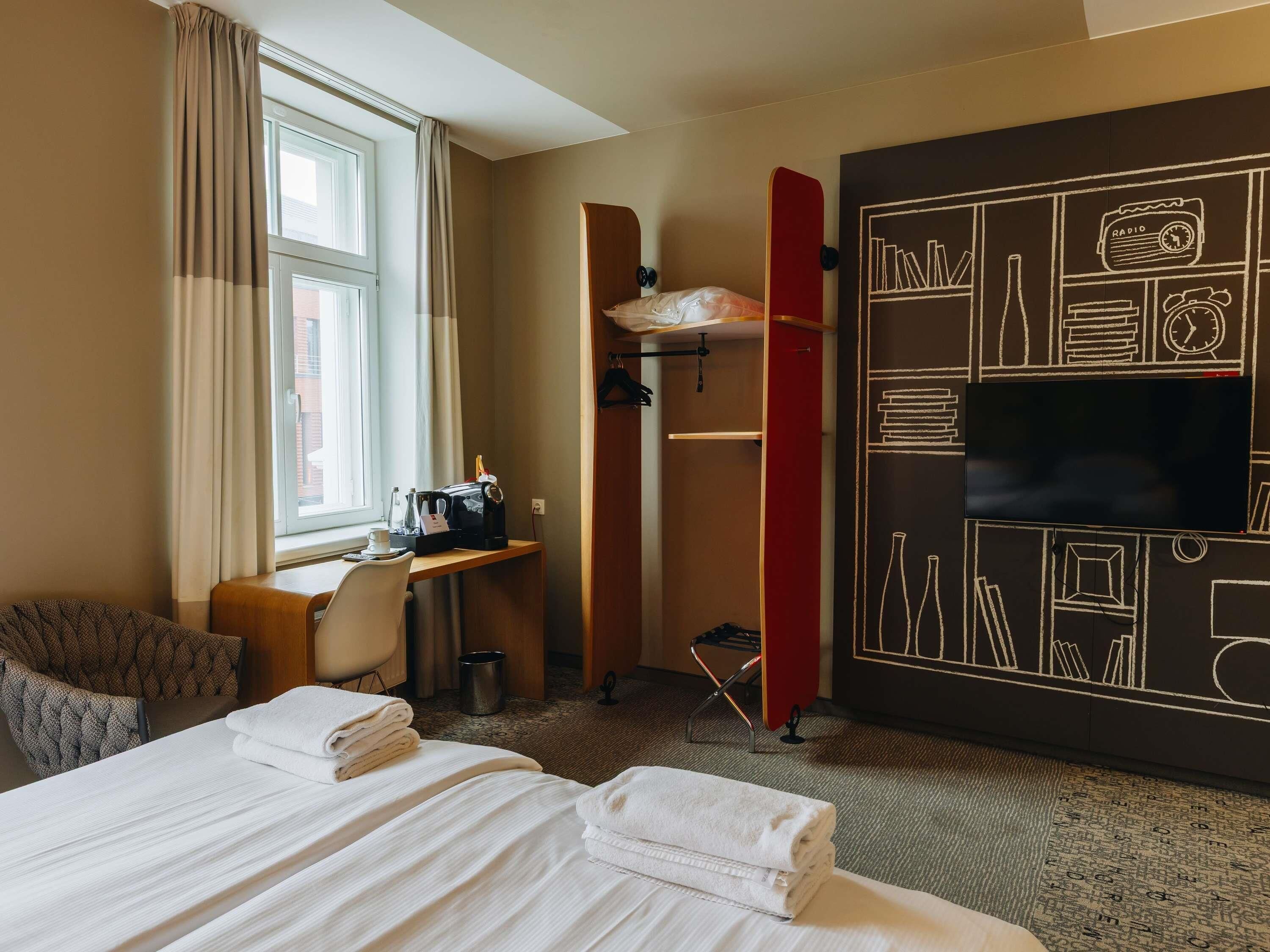 Ett hotellrum med två sängar, ett skrivbord med en dator, en tv och en garderob.