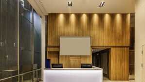 Un comptoir d’accueil au design moderne, un grand écran placé au-dessus, et un mur revêtu de panneaux en bois à l’arrière.