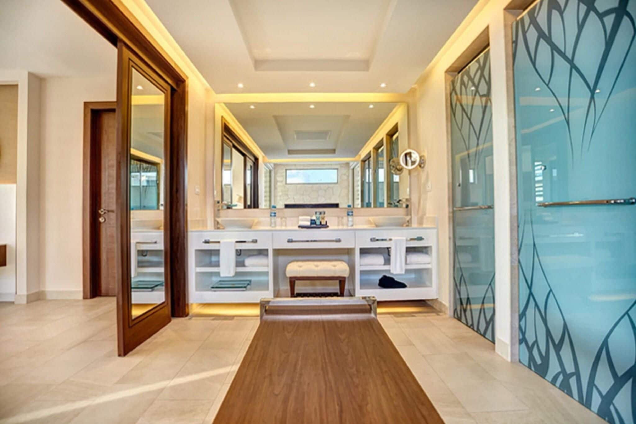 A modern bathroom with a large mirror, vanity, and a bench.
