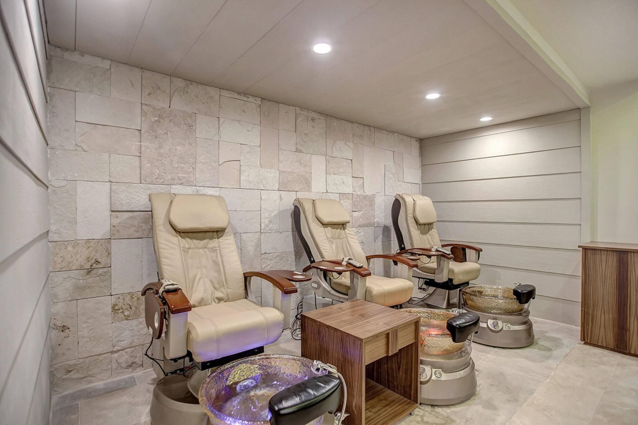 A room with four massage chairs, a wooden table, and a stone wall.