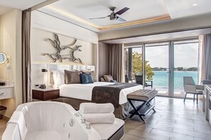 A modern hotel room with a large bed, a bathtub, and a balcony with a view of the sea. - Royalton Hideaway Negril (Negril)